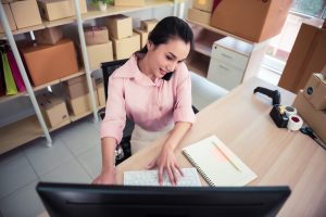 Woman multi-tasking typing on her desktop while on the phone